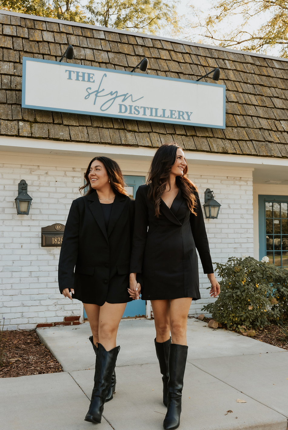 Melissa Miles and Emily Bettenga, founders of The Skyn Distillery, standing in front of their skincare and sauna studio in Wayzata, Minnesota, known for results-driven facials and personalized skincare rituals.